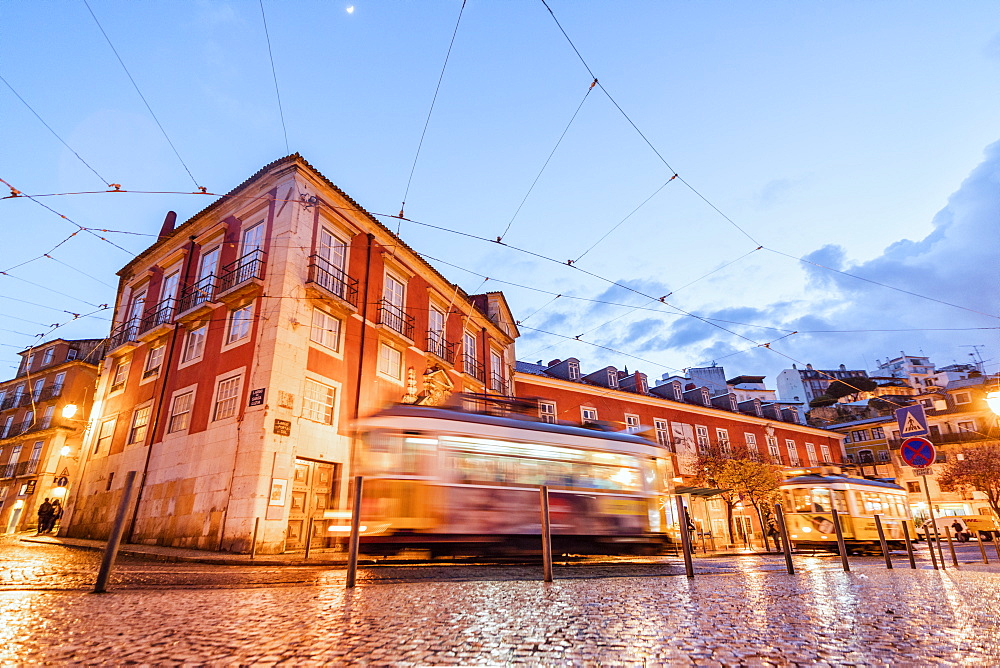 City lights on the typical architecture and old streets at dusk while the tram 28 proceeds, Alfama, Lisbon, Portugal, Europe