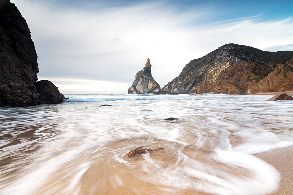 Ocean waves crashing on the sandy beach of Praia da Ursa surrounded by cliffs, Cabo da Roca, Colares, Sintra, Portugal, Europe