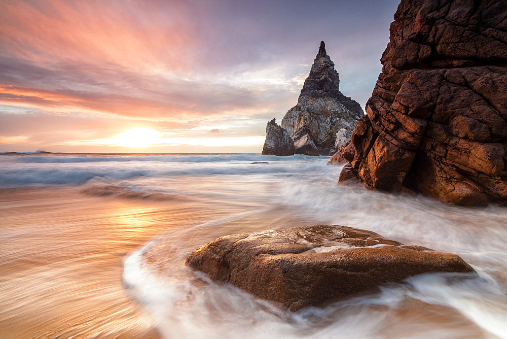 The fiery sky at sunset is reflected on the ocean waves and cliffs, Praia da Ursa, Cabo da Roca, Colares, Sintra, Portugal, Europe