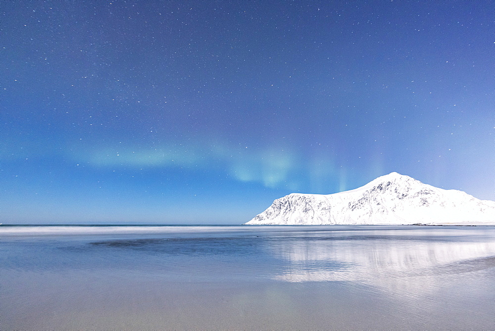 Northern Lights (Aurora borealis) on the snowy peaks reflected in the sea, Skagsanden beach, Flakstad, Nordland county, Lofoten Islands, Norway, Scandinavia, Europe