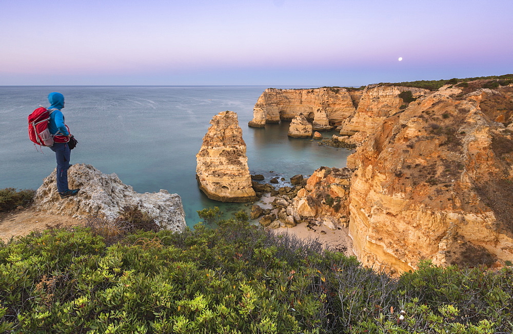 The photographer admires cliffs and ocean of Praia da Marinha at dawn, Caramujeira, Lagoa Municipality, Algarve, Portugal, Europe