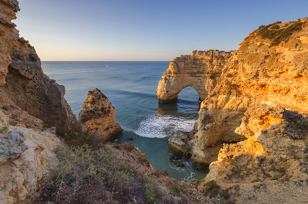 Sunrise on the cliffs and turquoise water of the ocean, Praia da Marinha, Caramujeira, Lagoa Municipality, Algarve, Portugal, Europe