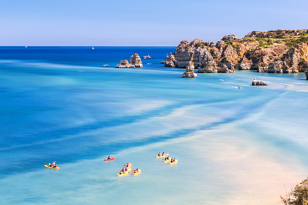 Canoes in the turquoise water of the Atlantic Ocean surrounding Praia Dona Ana beach, Lagos, Algarve, Portugal, Europe