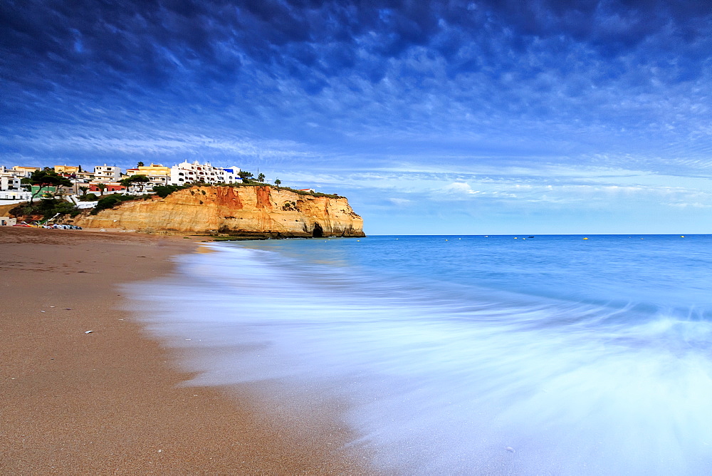 Ocean waves crashing on rocks and beach surrounding Carvoeiro village at sunset, Lagoa Municipality, Algarve, Portugal, Europe