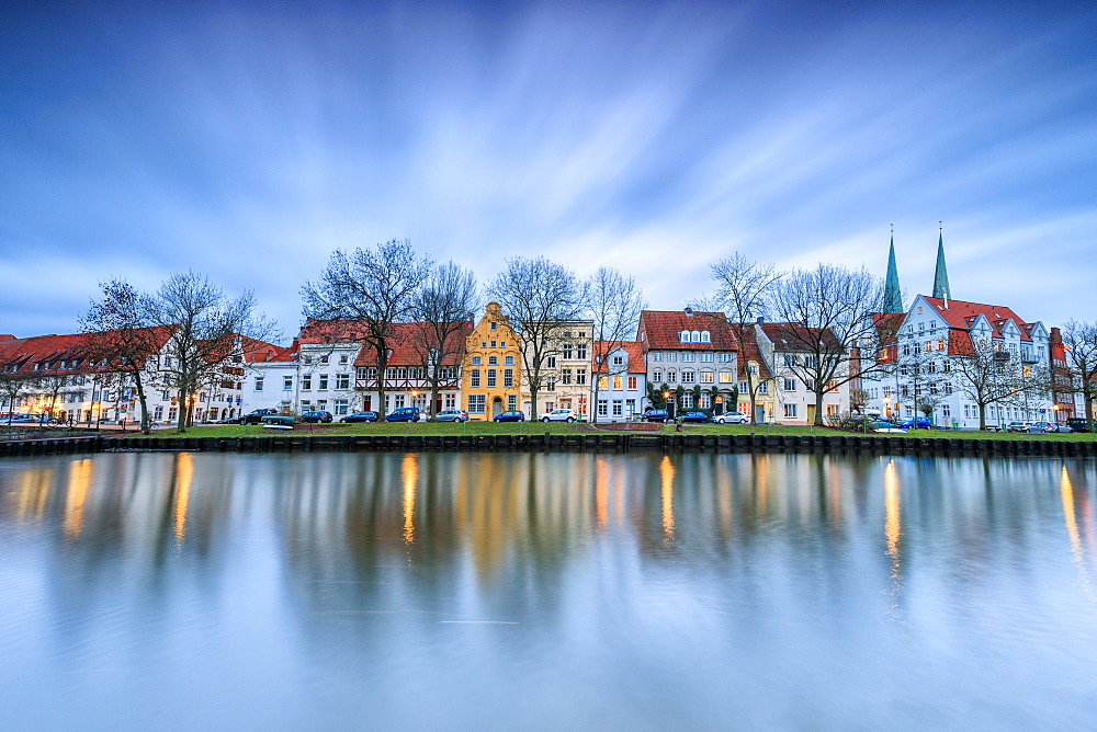 Clouds on the typical houses and towers of cathedral reflected in River Trave at dusk, Lubeck, Schleswig Holstein, Germany, Europe