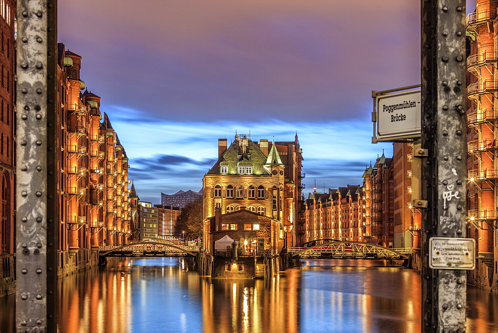 Blue dusk and lights are reflected in Poggenmohlenbrucke with water castle between bridges, Altstadt, Hamburg, Germany, Europe