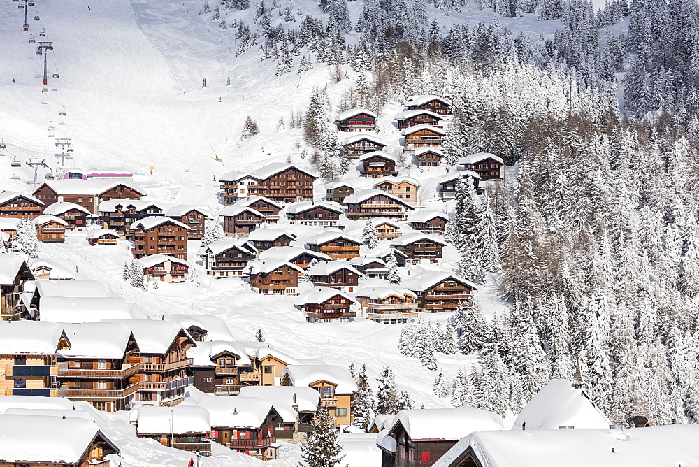 Snowy woods frame the typical alpine village and ski resort, Bettmeralp, district of Raron, canton of Valais, Switzerland, Europe