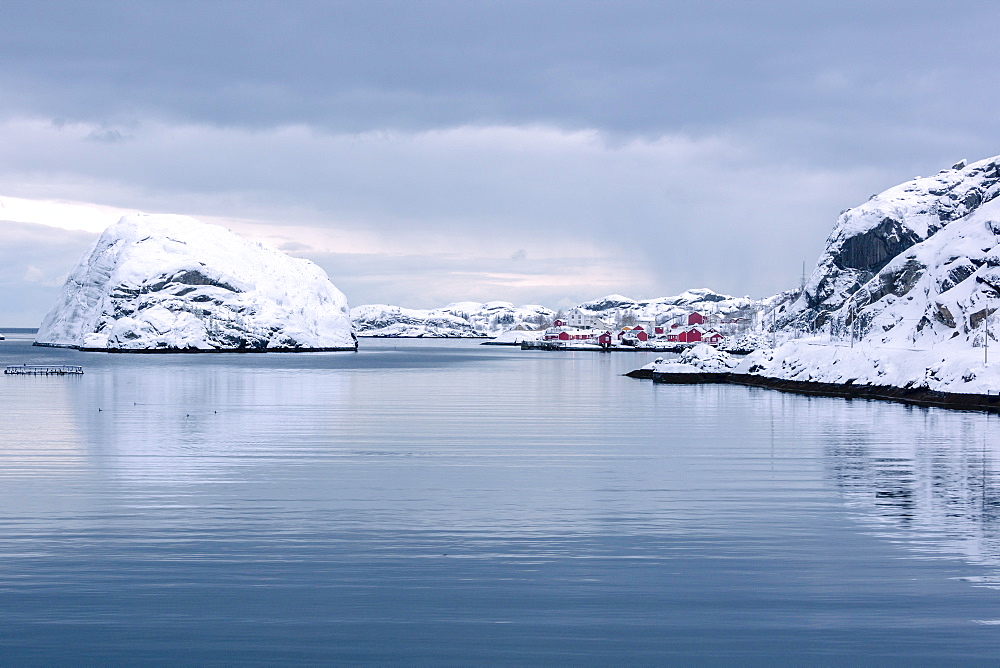 Cold sea and snowy peaks frame the fishing village at dusk, Nusfjord, Nordland, Lofoten Islands, Northern Norway, Scandinavia, Europe