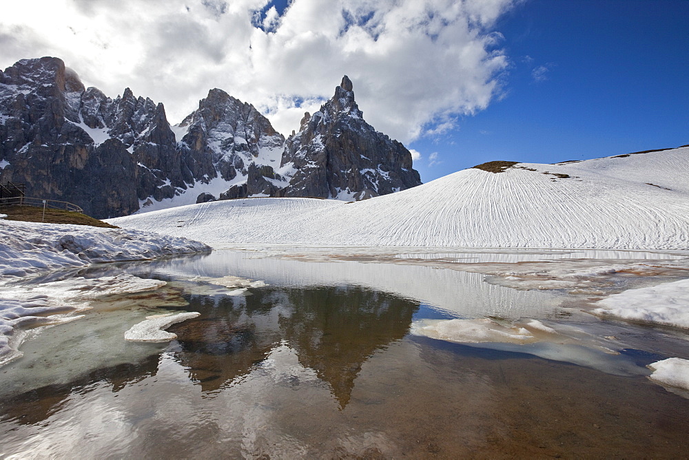 Snow is thawing leaving some puddles at the foot of the Pale di San Martino by San Martino di Castrozza, Dolomites, Trentino, Italy, Europe