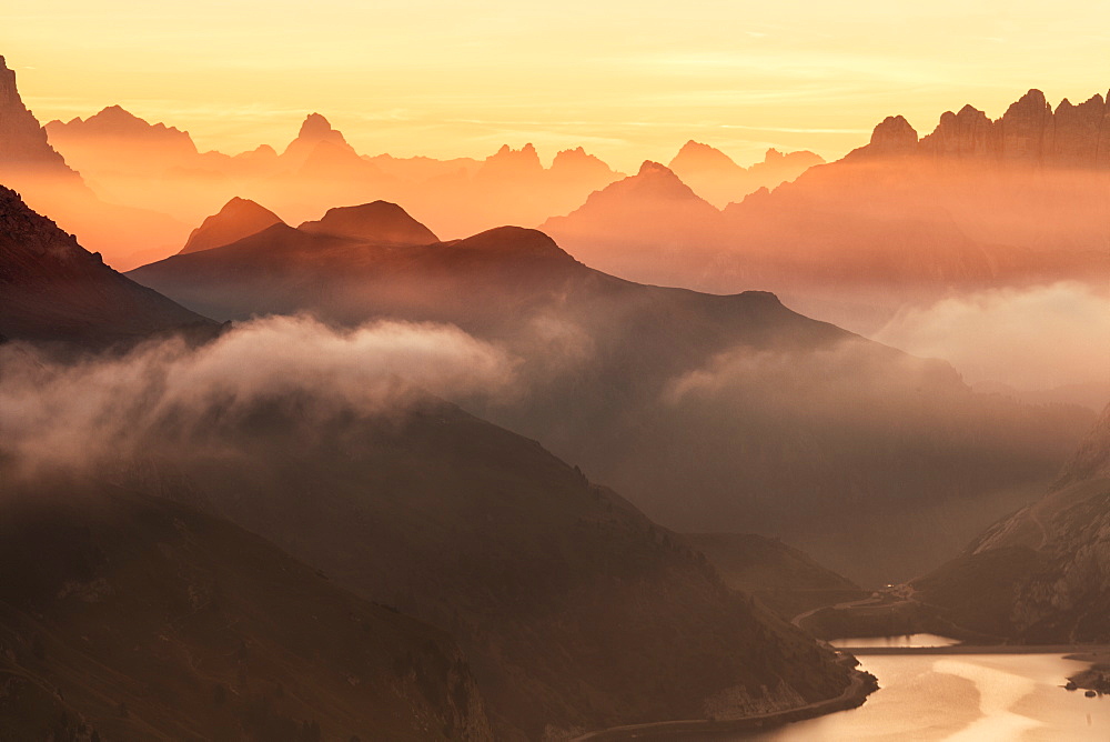 Orange sky at dawn and mist on peaks of Dolomites and Fedaia Pass, Cima Belvedere, Val di Fassa, Trentino-Alto Adige, Italy, Europe