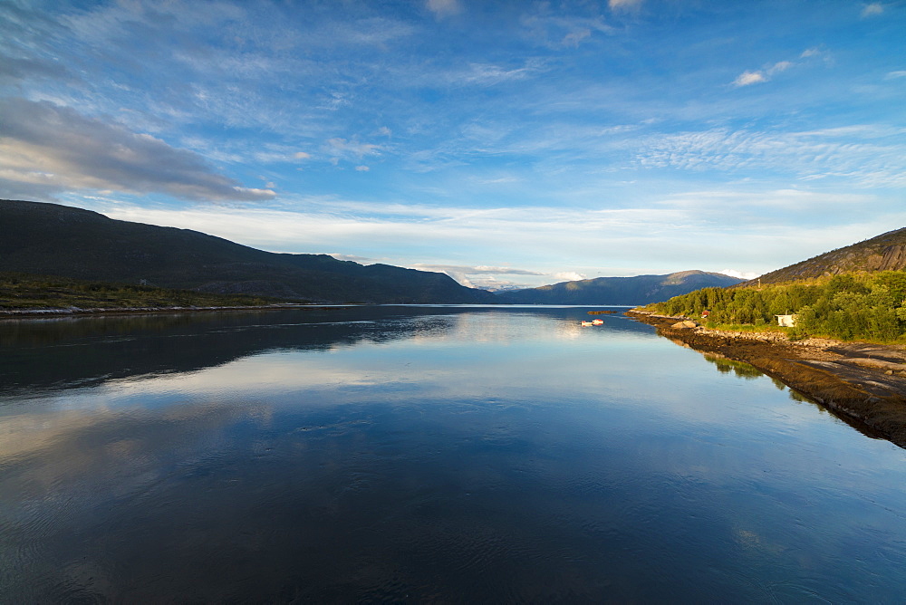 Light of the midnight sun illuminates the clear water of blue sea and green woods, Anepollen Fjord, Nordland, Norway, Scandinavia, Europe