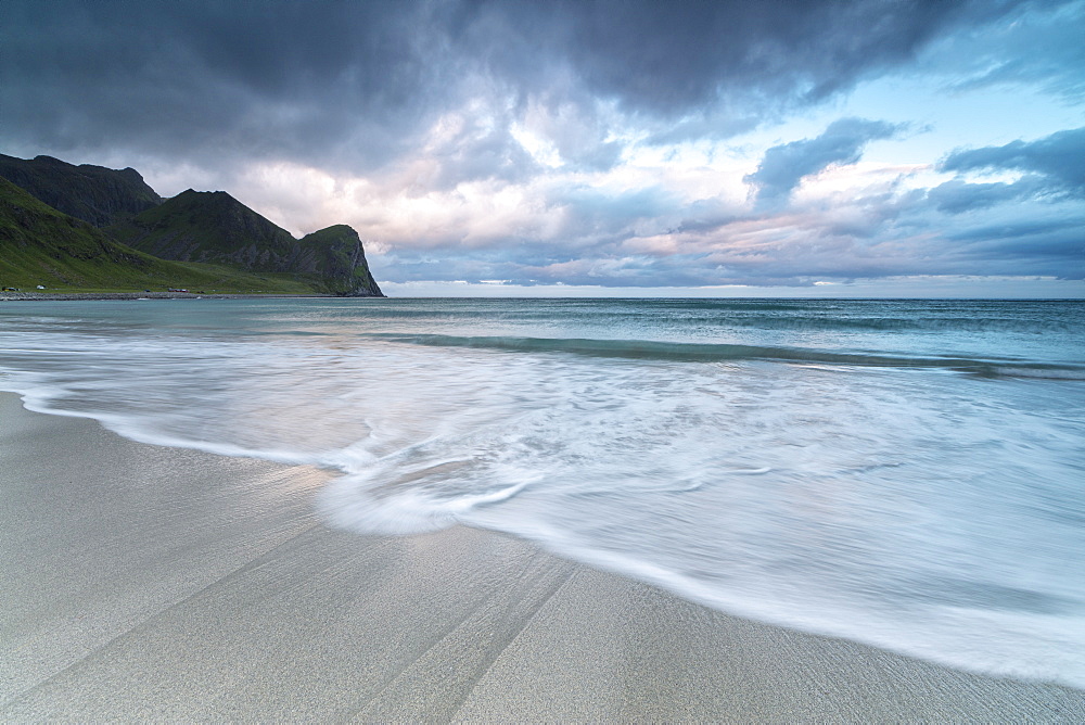 Pink clouds of midnight sun reflected on the blue sea and sandy beach, Unstad, Vestvagoy, Lofoten Islands, Arctic, Norway, Scandinavia, Europe