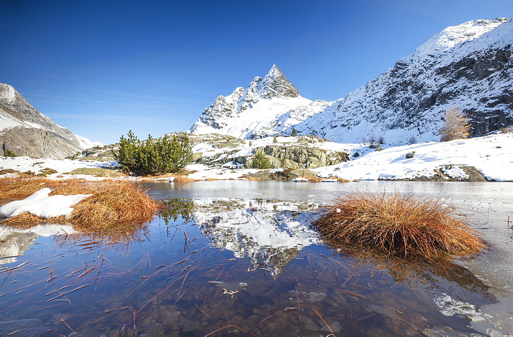 Snowy peaks are reflected in the alpine lake partially frozen, Lejets Crap Alv (Crap Alv Laiets), Canton of Graubunden, Engadine, Switzerland, Europe