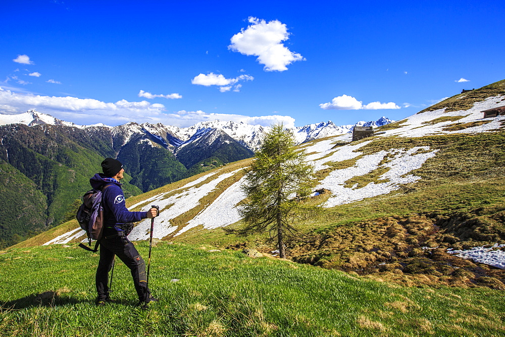 Hiker contemplating the landscape that can be seen from the Cima della Rosetta in the Orobie Alps in the spring, Lombardy, Italy, Europe