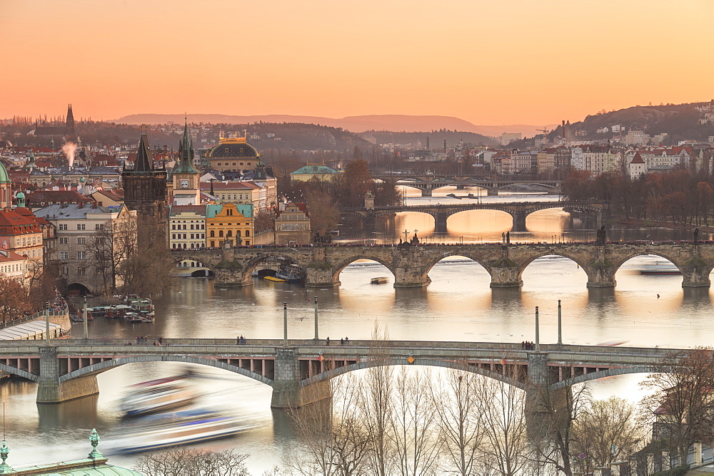 Orange sky at sunset on the historical bridges and buildings reflected on Vltava River, Prague, Czech Republic, Europe