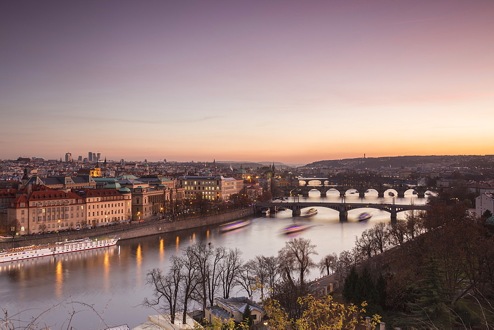 Pink sky on historical bridges and buildings reflected on Vltava River at sunset, Prague, Czech Republic, Europe