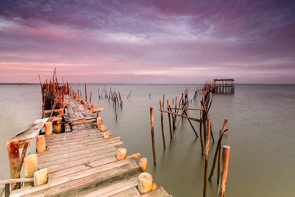 Pink sky at dawn on the Palafito Pier in the Carrasqueira Natural Reserve of Sado River, Alcacer do Sal, Setubal, Portugal, Europe