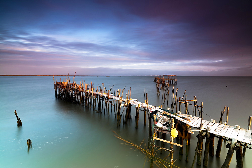 Sunrise and clouds on the Palafito Pier in the Carrasqueira Natural Reserve of Sado River, Alcacer do Sal, Setubal, Portugal, Europe