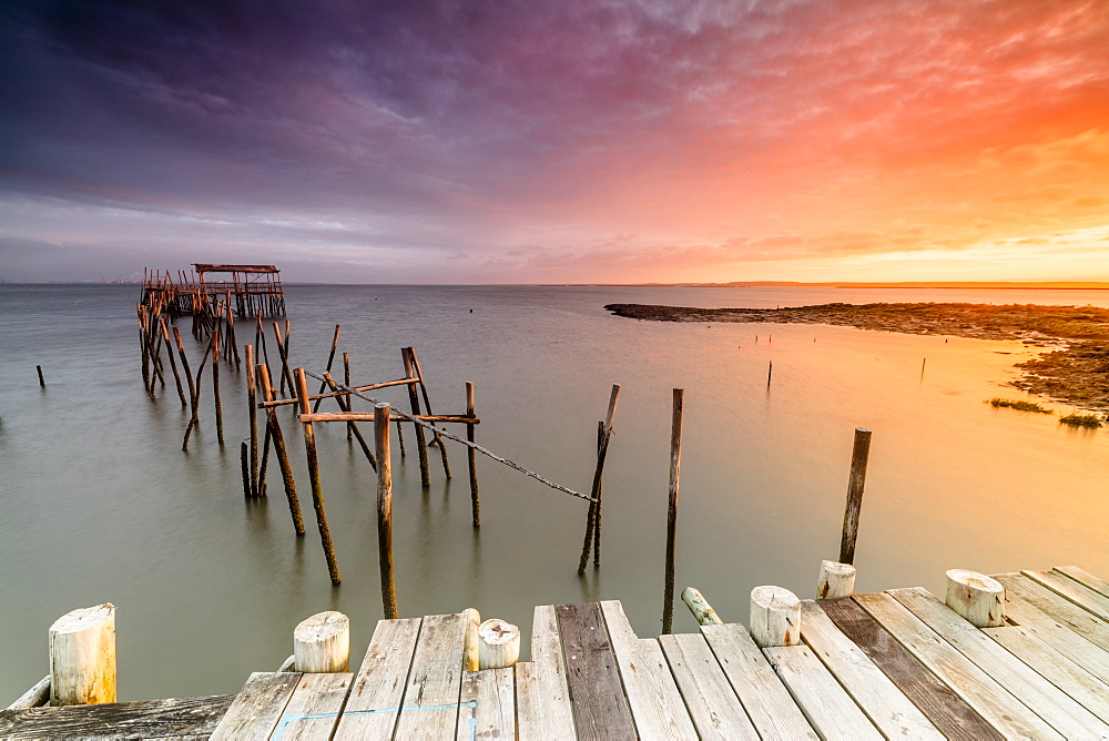 Fiery sky at dawn on the Palafito Pier in the Carrasqueira Natural Reserve of Sado River, Alcacer do Sal, Setubal, Portugal, Europe