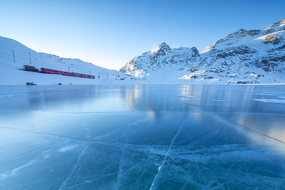 The Bernina Express train runs beside the frozen Lago Bianco, Bernina Pass, canton of Graubunden, Engadine, Switzerland, Europe