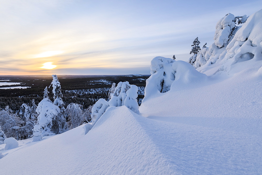 The sun frames the snowy landscape and woods in the cold arctic winter, Ruka, Kuusamo, Ostrobothnia region, Lapland, Finland, Europe