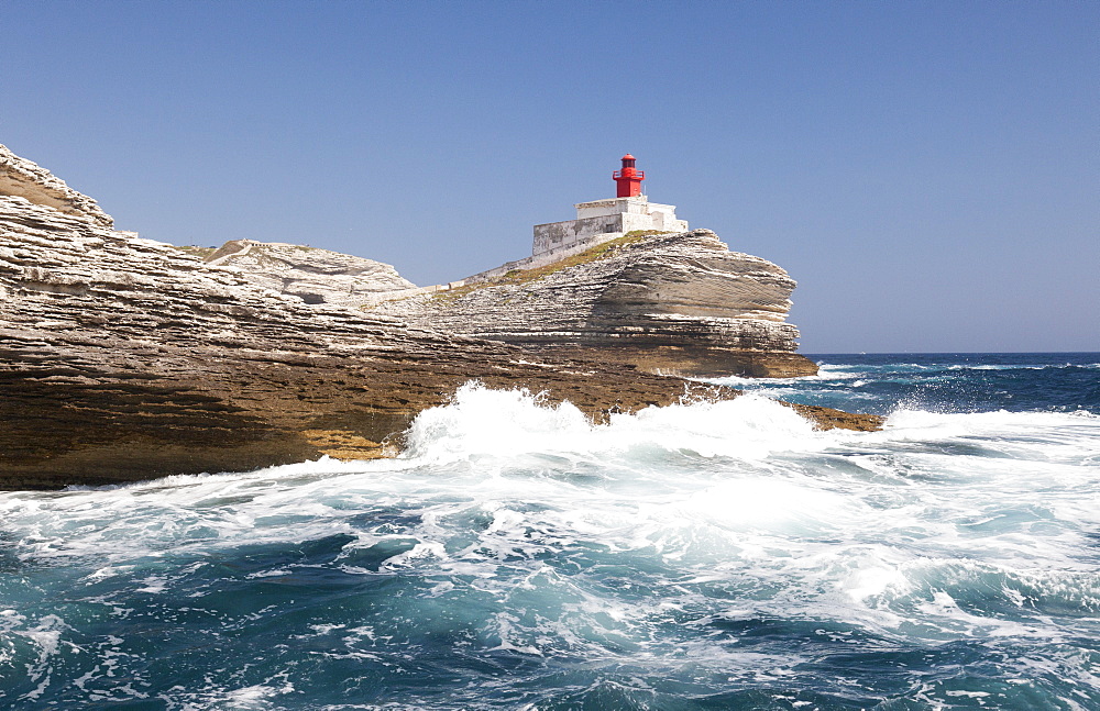 Waves of the turquoise sea crashing on the granite white cliffs and lighthouse, Lavezzi Islands, Bonifacio, Corsica, France, Mediterranean, Europe