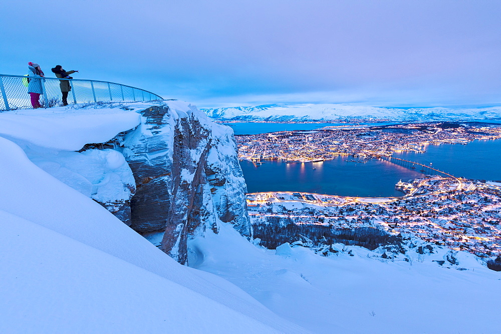 People admire the city of Tromso at dusk from the mountain top reached by the Fjellheisen cable car, Troms, Northern Norway, Scandinavia, Europe