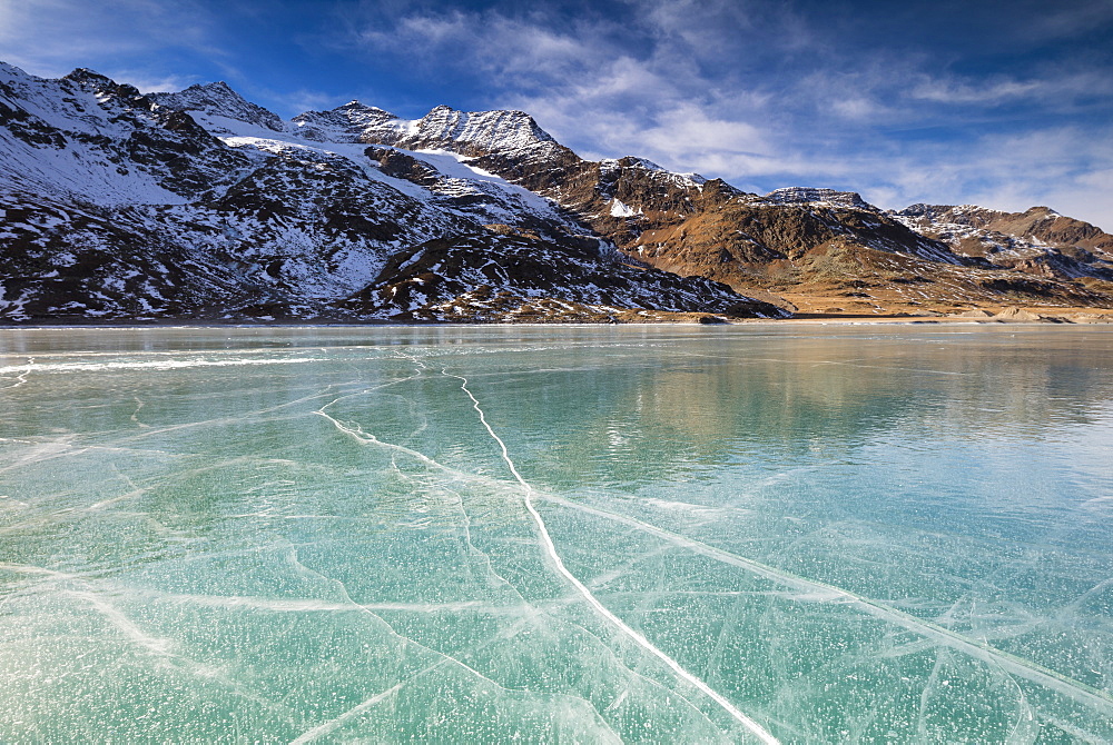 The snowy peaks frame the frozen turquoise water of White Lake (Lago Bianco), Bernina Pass, Canton of Graubunden, Engadine, Switzerland, Europe