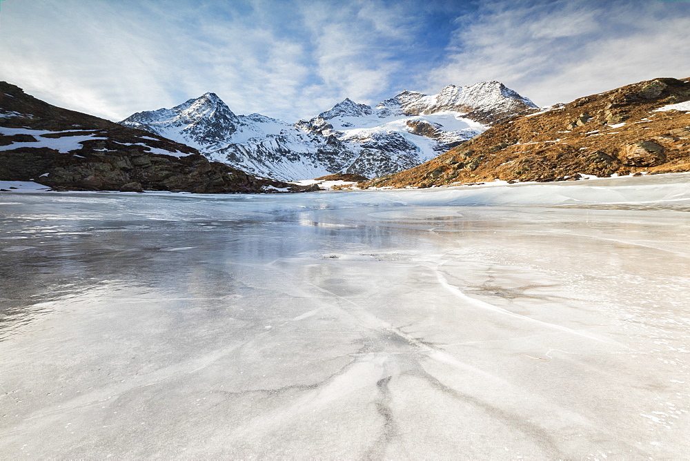 Blue sky and clouds on frozen Lej Nair surrounded by snowy peaks, Bernina Pass, Canton of Graubunden, Engadine, Switzerland, Europe