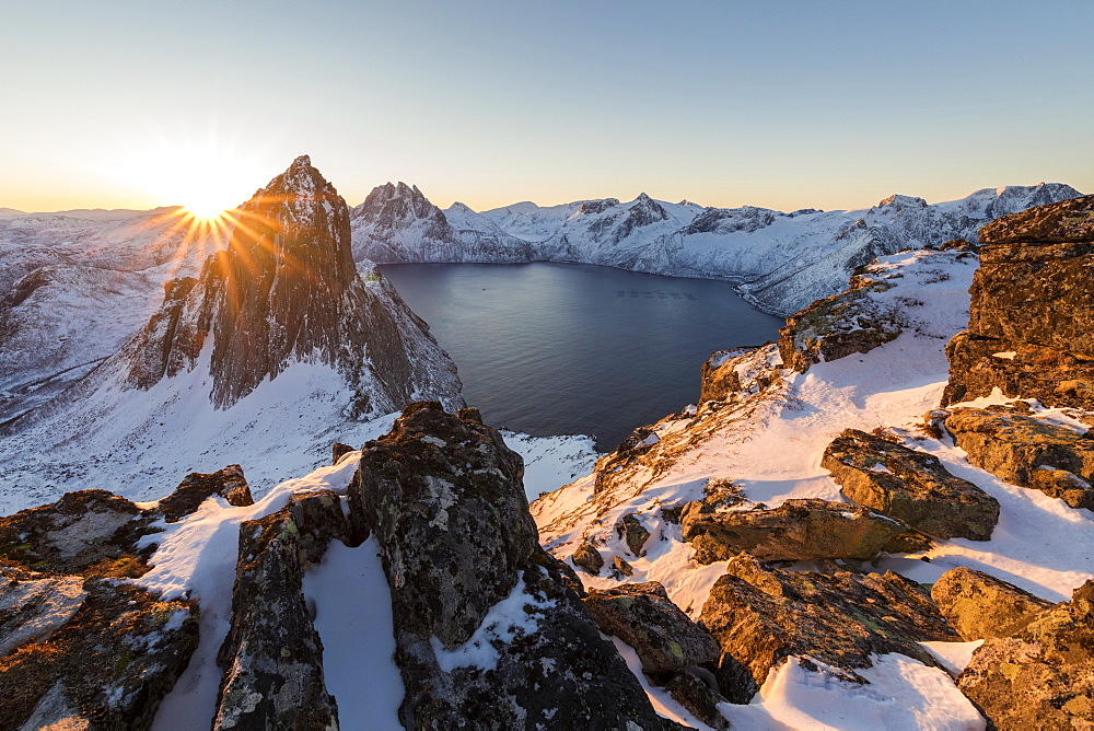 First light of sunrise on Mount Segla and Mefjorden framed by the frozen sea seen from peak Hesten, Senja, Troms, Norway, Scandinavia, Europe