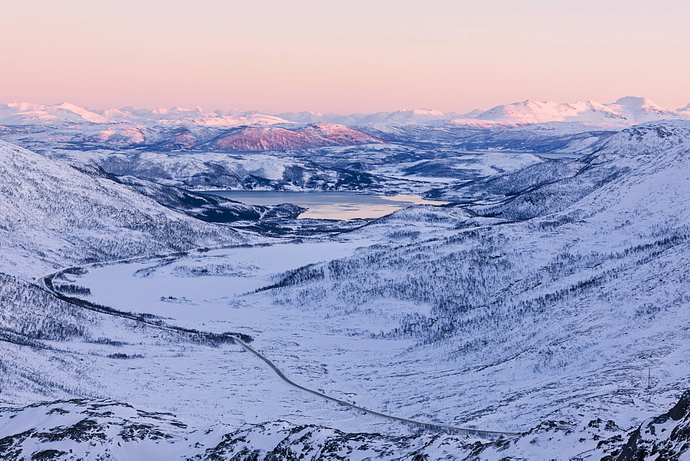 Pink sky at sunset on the snowy landscape and frozen sea surrounding Fjordbotn, Lysnes, Senja, Troms, Norway, Scandinavia, Europe