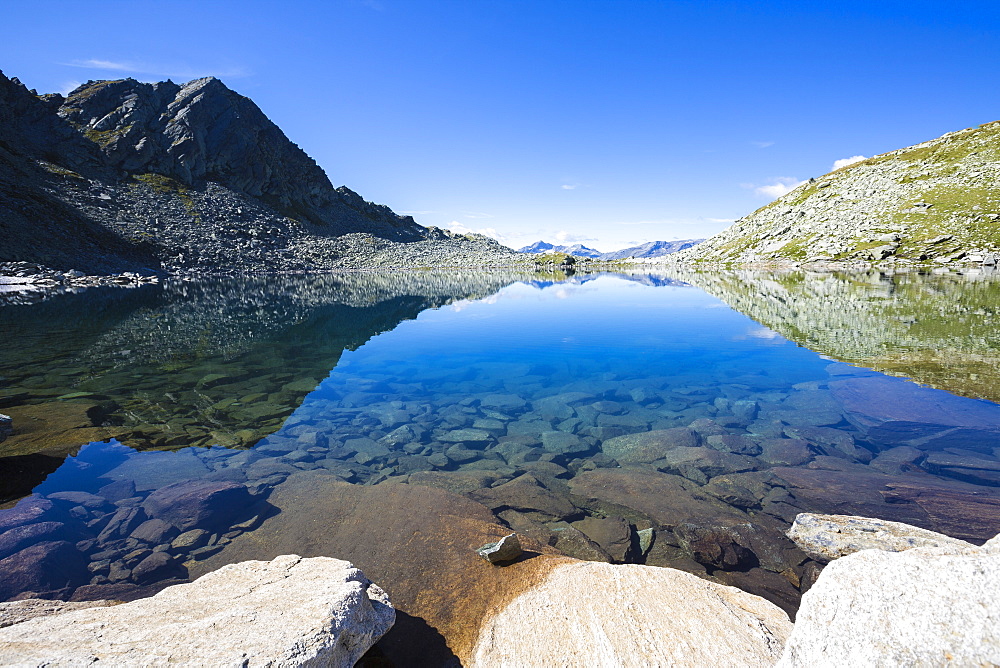 Blue sky and rocky peaks reflected in the blue Lago Nero, Chiavenna Valley, Valtellina, Lombardy, Italy, Europe