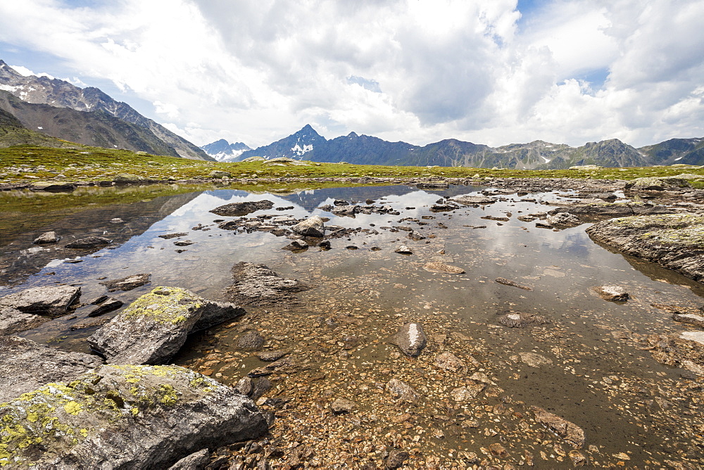 Clouds on rocky peaks reflected in the alpine Lake Schottensee, Fluela Pass, canton of Graubunden, Engadine, Switzerland, Europe