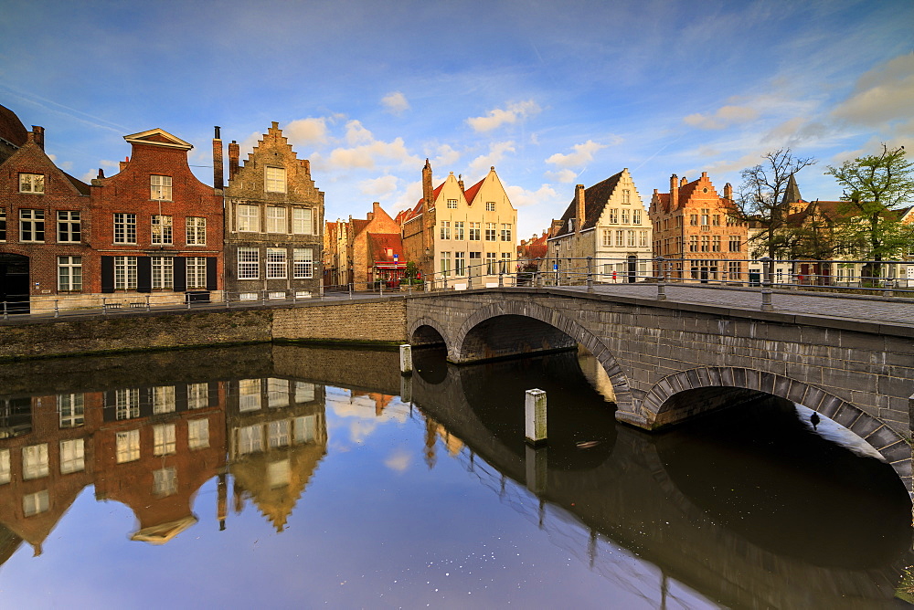 First light of sunrise on the historic buildings and bridge reflected in the typical canal, Bruges, West Flanders, Belgium, Europe