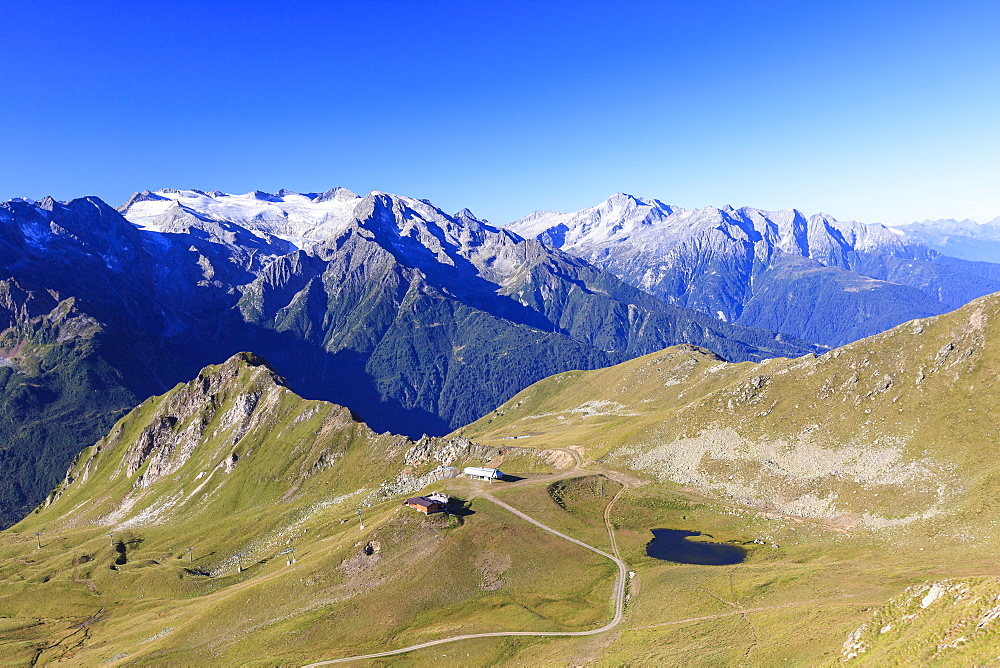 Green meadows and alpine lake framed by the high peaks in the Adamello Ski Area, Tonale Pass, Valcamonica, Lombardy, Italy, Europe