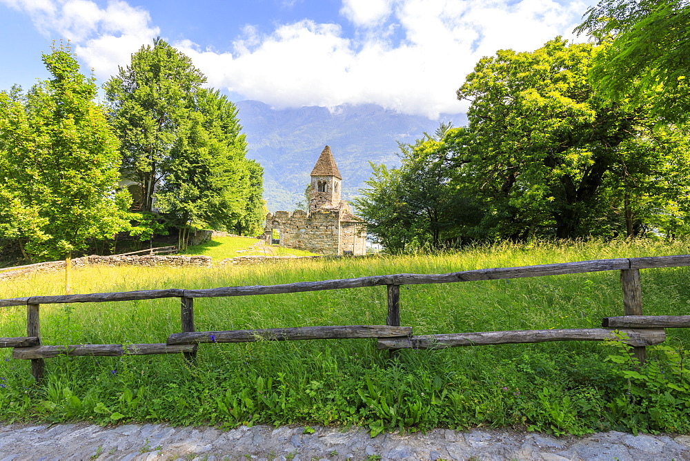 The medieval Abbey of San Pietro in Vallate framed by meadows, Piagno, Sondrio province, Lower Valtellina, Lombardy, Italy, Europe