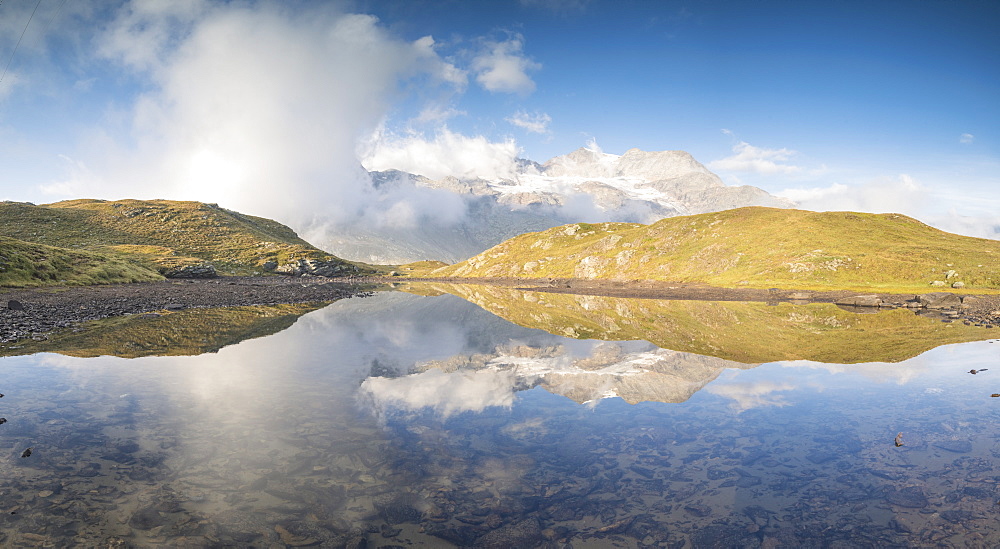 Panoramic of mountain peaks reflected in lake, Bernina Pass, Poschiavo Valley, Engadine, Canton of Graubunden, Switzerland, Europe