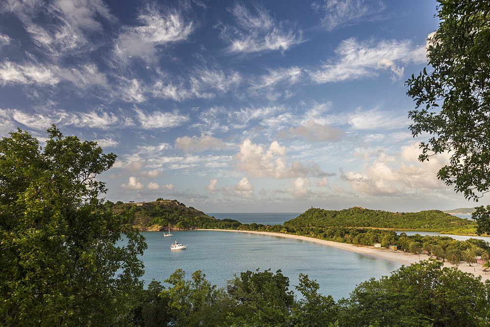 The clouds are illuminated by the setting sun on Deep Bay a stretch of sand hidden by lush vegetation, Antigua, Leeward Islands, West Indies, Caribbean, Central America