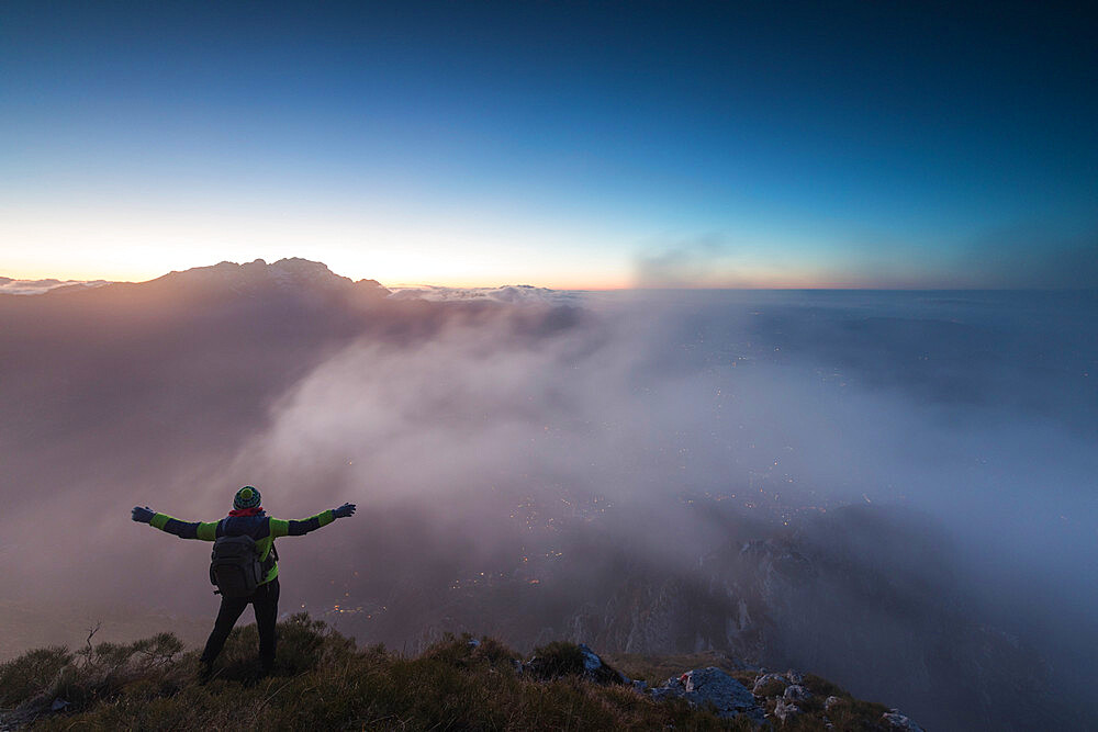 Hiker on top of Monte Coltignone at dawn, province of Lecco, Lombardy, Italy, Europe