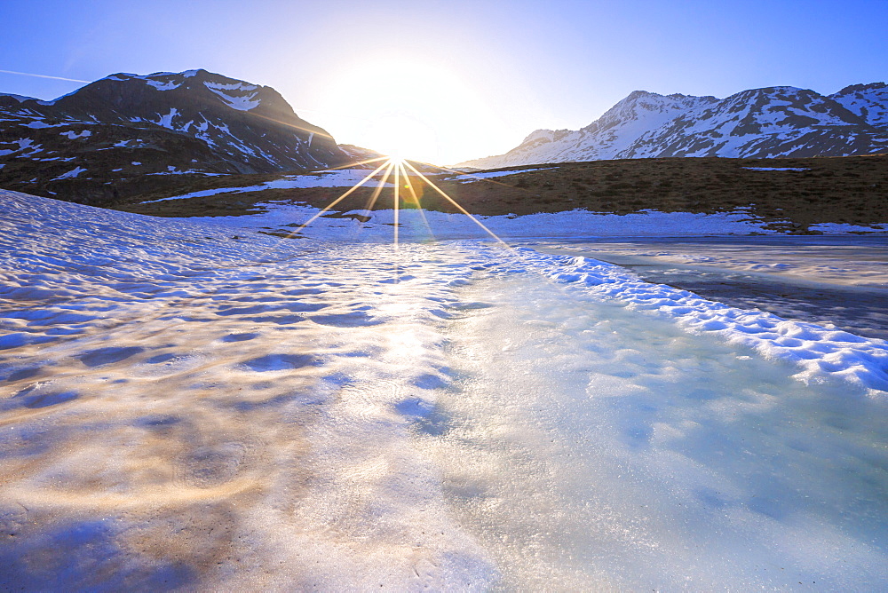 Sunburst on Lake Andossi during thaw, Chiavenna Valley, Spluga Valley, Sondrio province, Valtellina, Lombardy, Italy, Europe