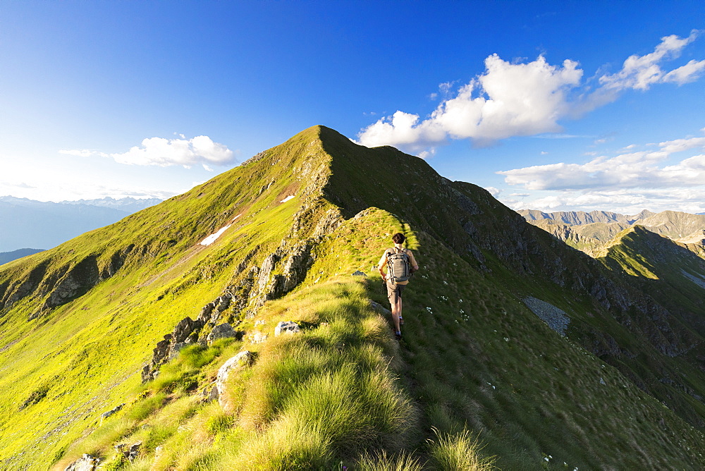 Hiker on steep ridge on the ascent towards Monte Azzarini, San Marco Pass, Albaredo Valley, Orobie Alps, Lombardy, Italy, Europe