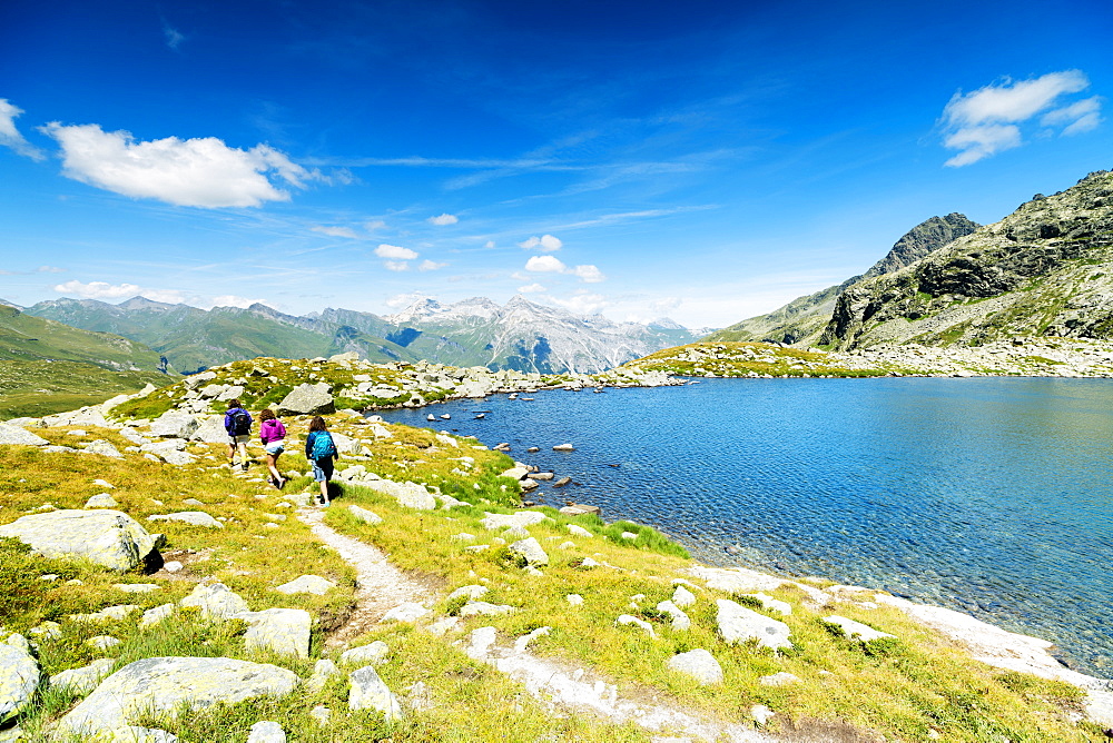 Hikers on footpath on the shore of lake Bergsee, Spluga Pass, canton of Graubunden, Switzerland, Europe