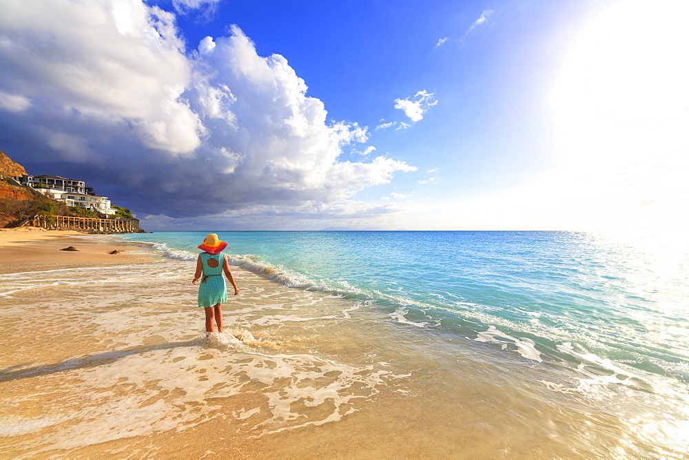 Rear view of woman with hat walking on Ffryes Beach, Antigua, Antigua and Barbuda, Leeward Islands, West Indies, Caribbean, Central America