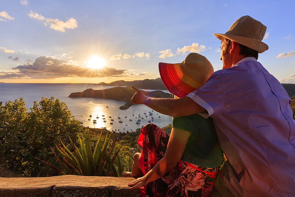 Couple look towards English Harbour from Shirley Heights at sunset, Antigua, Antigua and Barbuda, Leeward Islands, West Indies, Caribbean, Central America