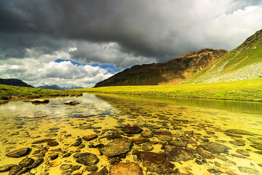 Storm clouds on Piz Umbrail reflected in the pristine alpine lake, Stelvio Pass, Braulio Valley, Valtellina, Lombardy, Italy, Europe