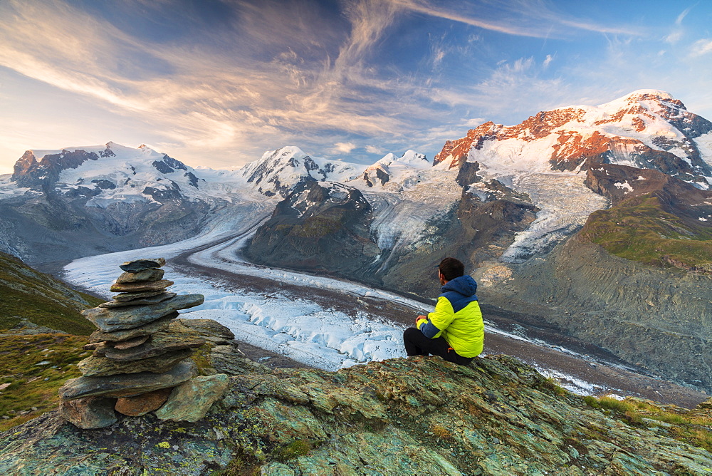 Hiker sitting on rocks looking towards Monte Rosa glacier, Zermatt, canton of Valais, Swiss Alps, Switzerland, Europe