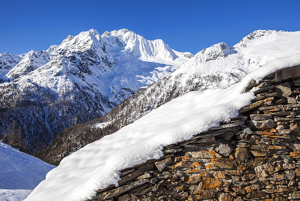 Stone hut covered with snow with Monte Disgrazia on background, Alpe dell'Oro, Valmalenco, Valtellina, Lombardy, Italy, Europe