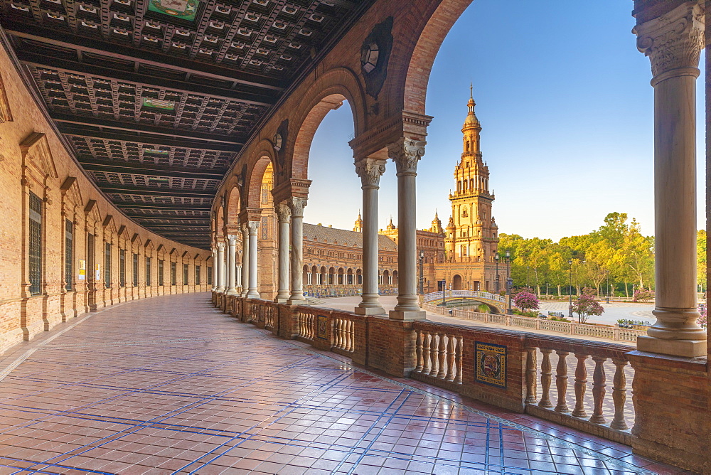 Sunrise on the old tower seen from colonnade of the semi-circular portico, Plaza de Espana, Seville, Andalusia, Spain, Europe