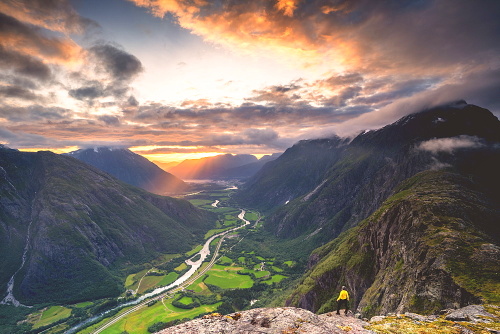 Elevated view of man standing on Romsdalseggen ridge admiring Rauma valley during sunset, Andalsnes, More og Romsdal, Norway, Scandinavia, Europe