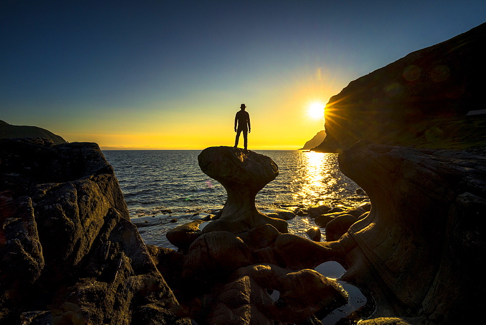 Silhouette of man admiring sunset standing on top of Kannesteinen rock, Oppedal, Vagsoy, Sogn og Fjordane county, Norway, Scandinavia, Europe